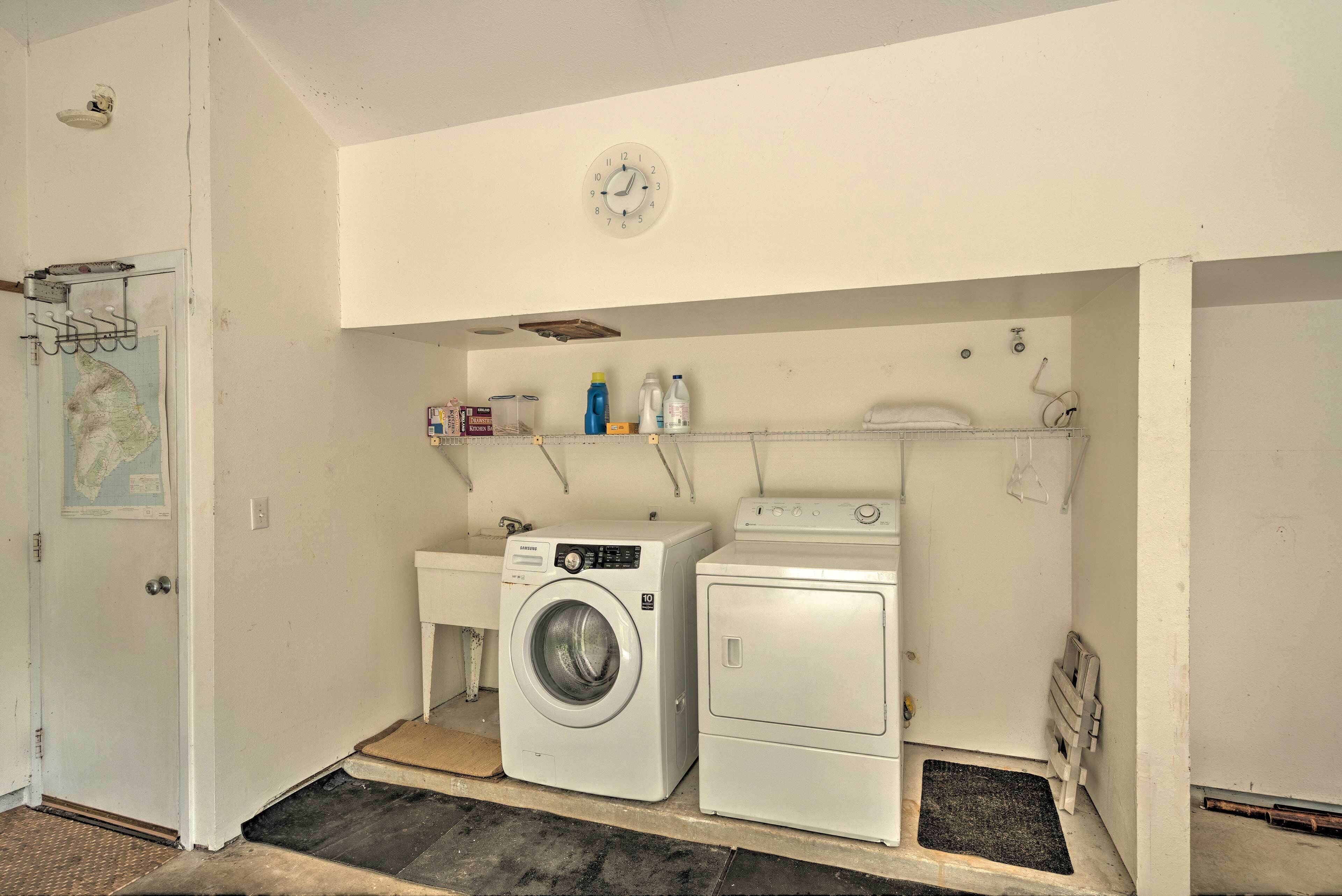 Une buanderie équipée d’un lave-linge, d’un sèche-linge et d’une horloge murale.