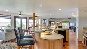 A spacious living area with a curved wooden island, a sofa, and a dining table. - Hilo Home w/ Private Deck + Stunning Ocean Views! (Hilo)