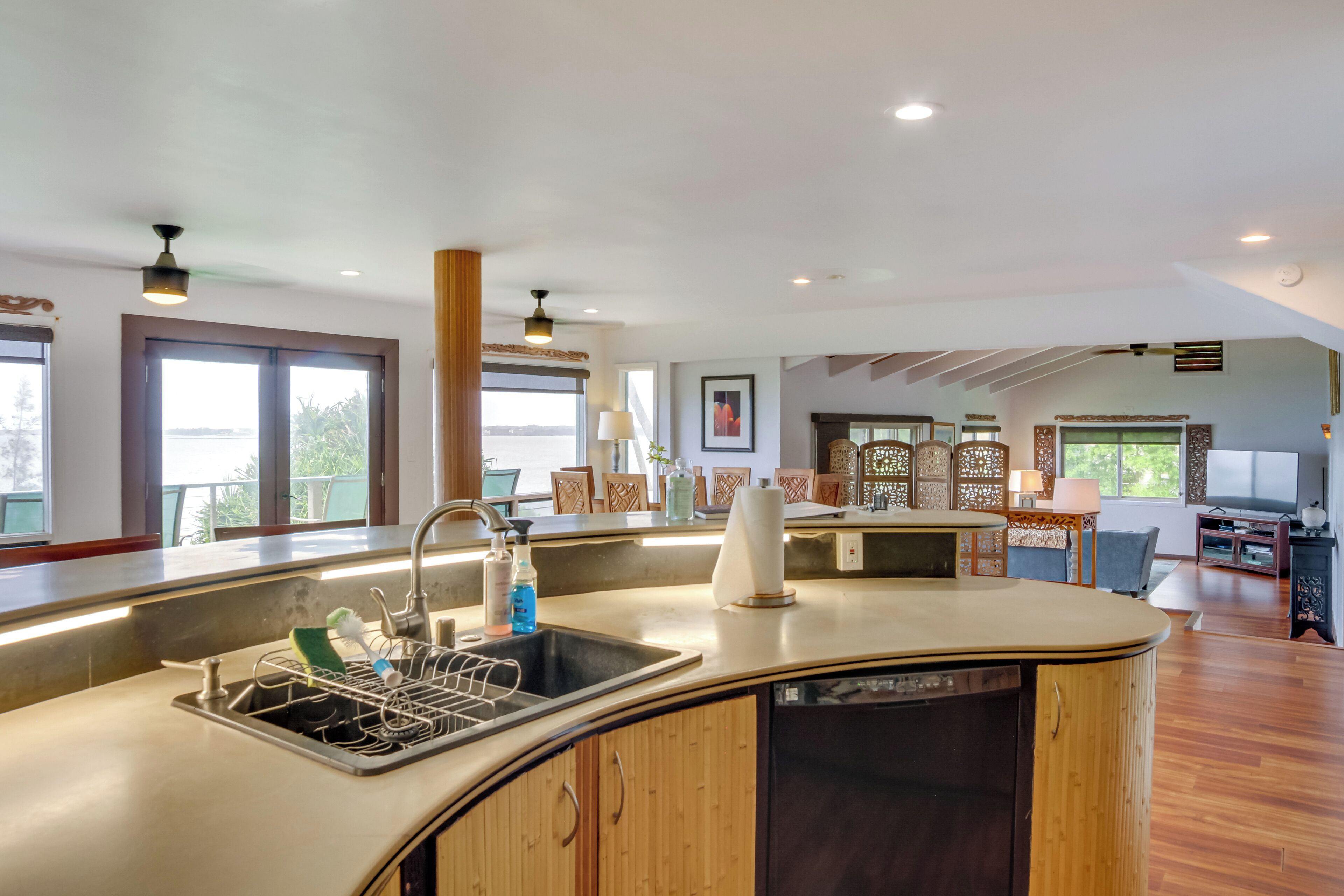 Una cocina moderna con una isla curva, lavavajillas integrado y un amplio ventanal con vistas al exterior.