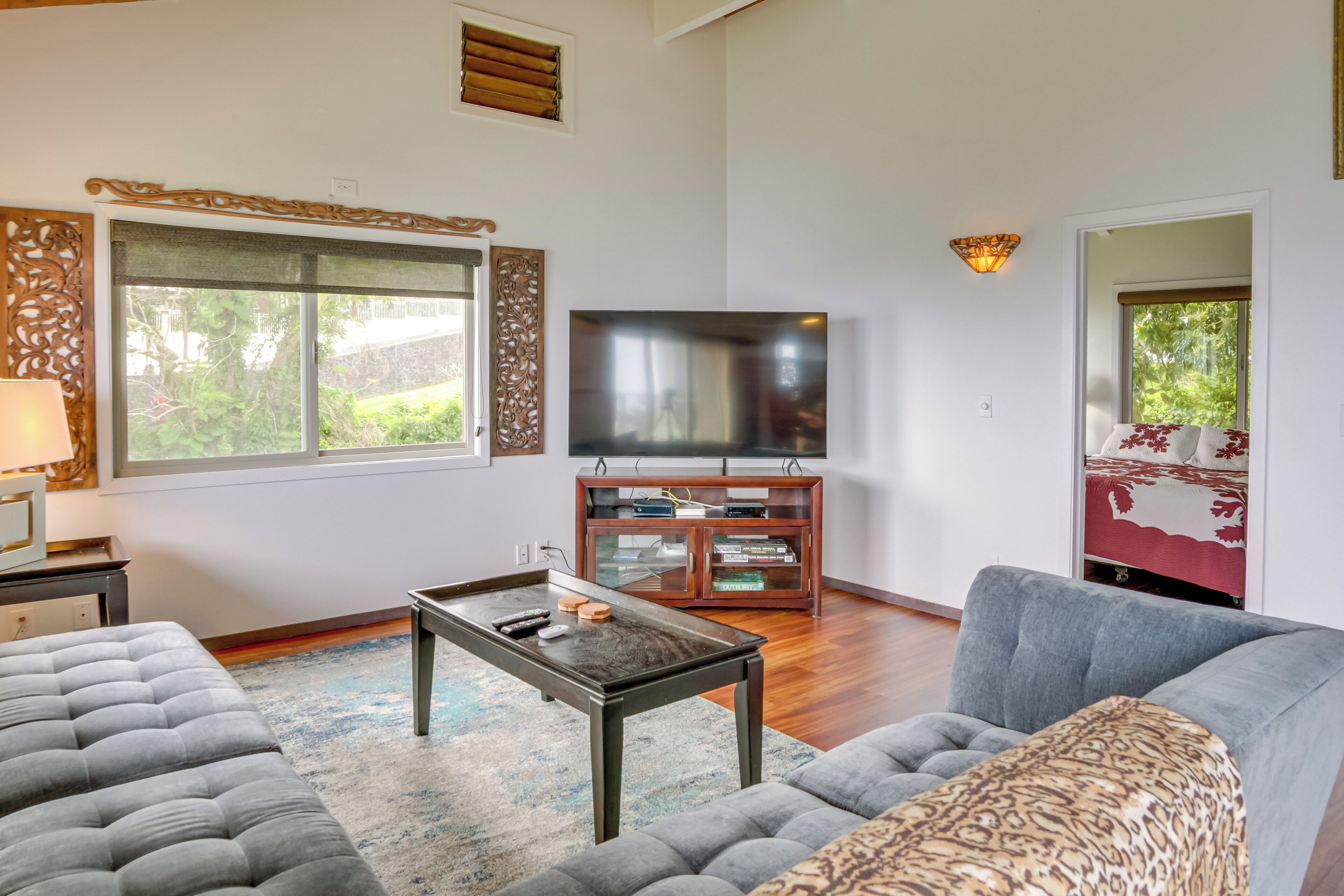 A living room with a flat-screen TV, a sofa, a coffee table, and a patterned ottoman.