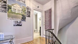 A hallway with a staircase, wooden flooring, a glass table with a box, and a door with a sign. - Charming Springfield Apt < 2 Mi to Downtown! (Springfield)