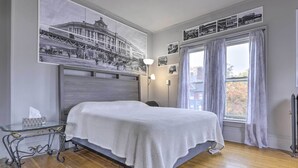 A bedroom with a bed, a nightstand, a wall-mounted lamp, and a window with curtains. - Charming Springfield Apt < 2 Mi to Downtown! (Springfield)