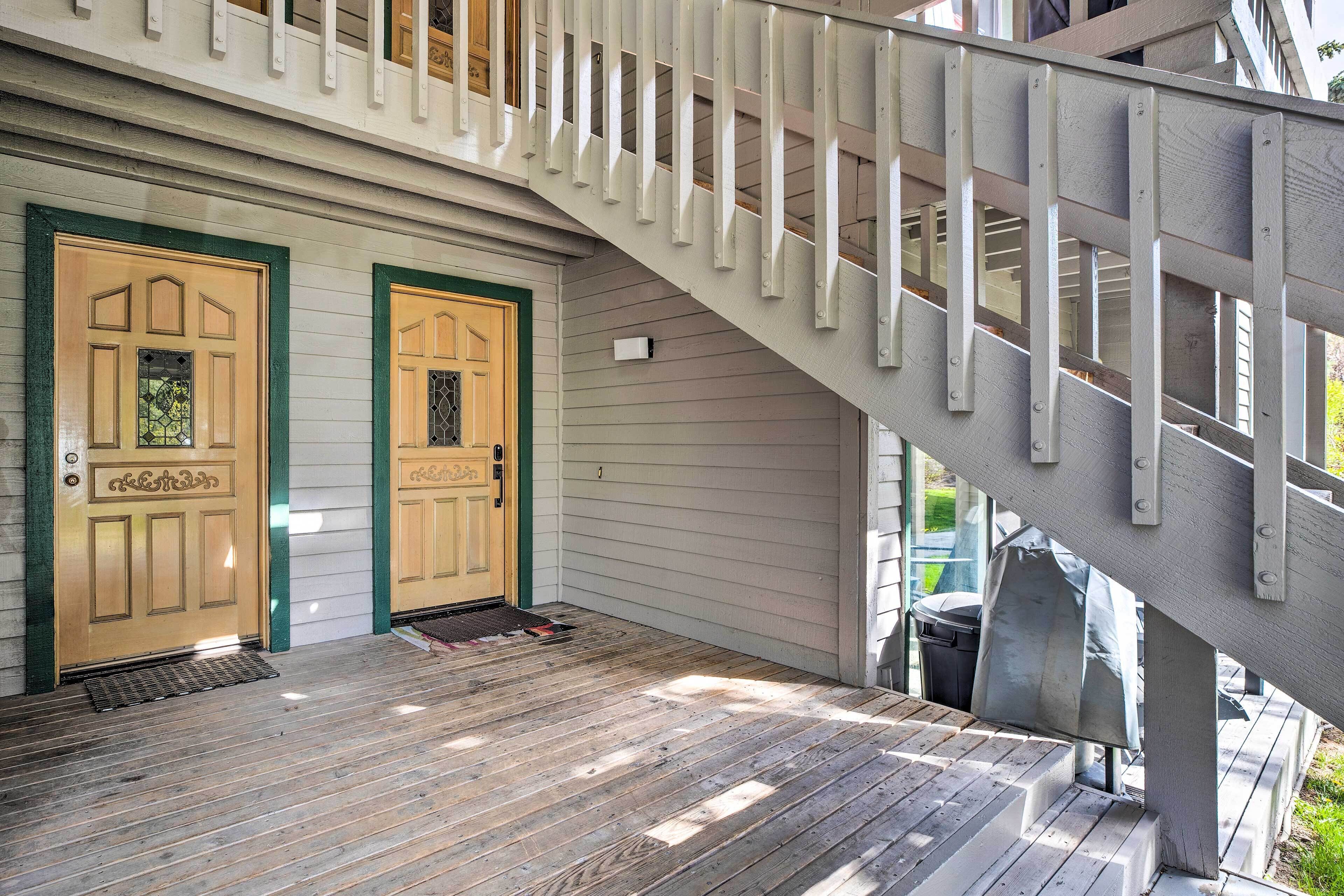 A wooden staircase with a white railing leading to a porch with two doors.