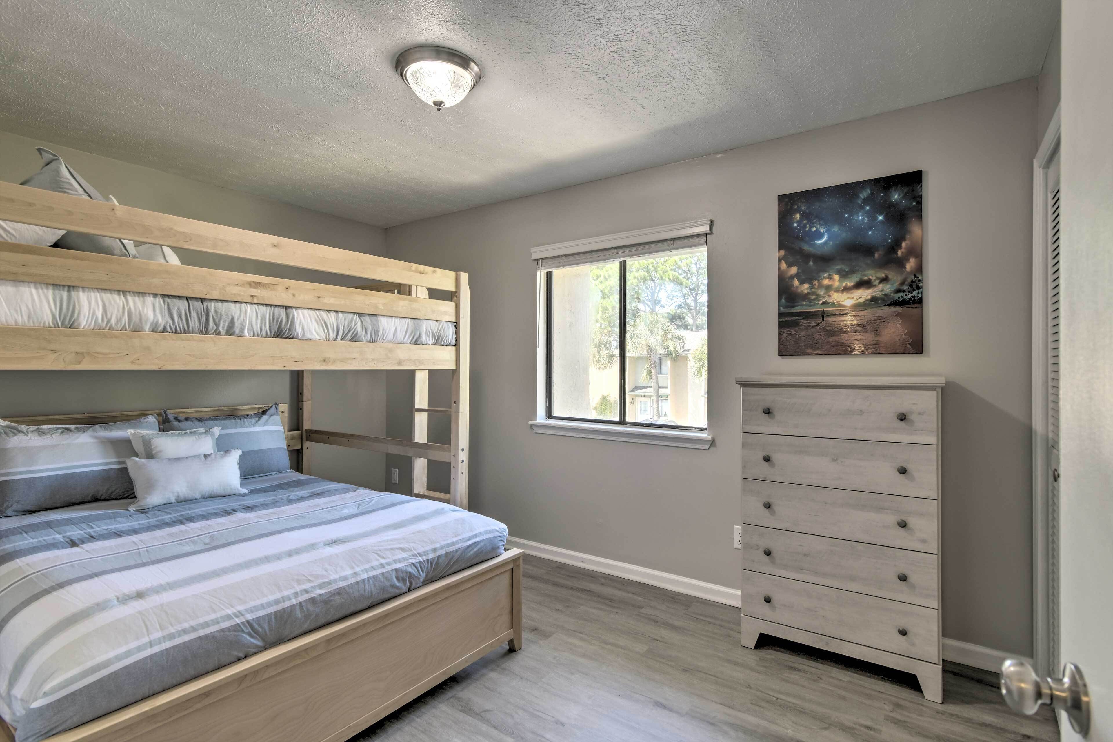 A bedroom with a bunk bed, a dresser, a window, and a painting on the wall.