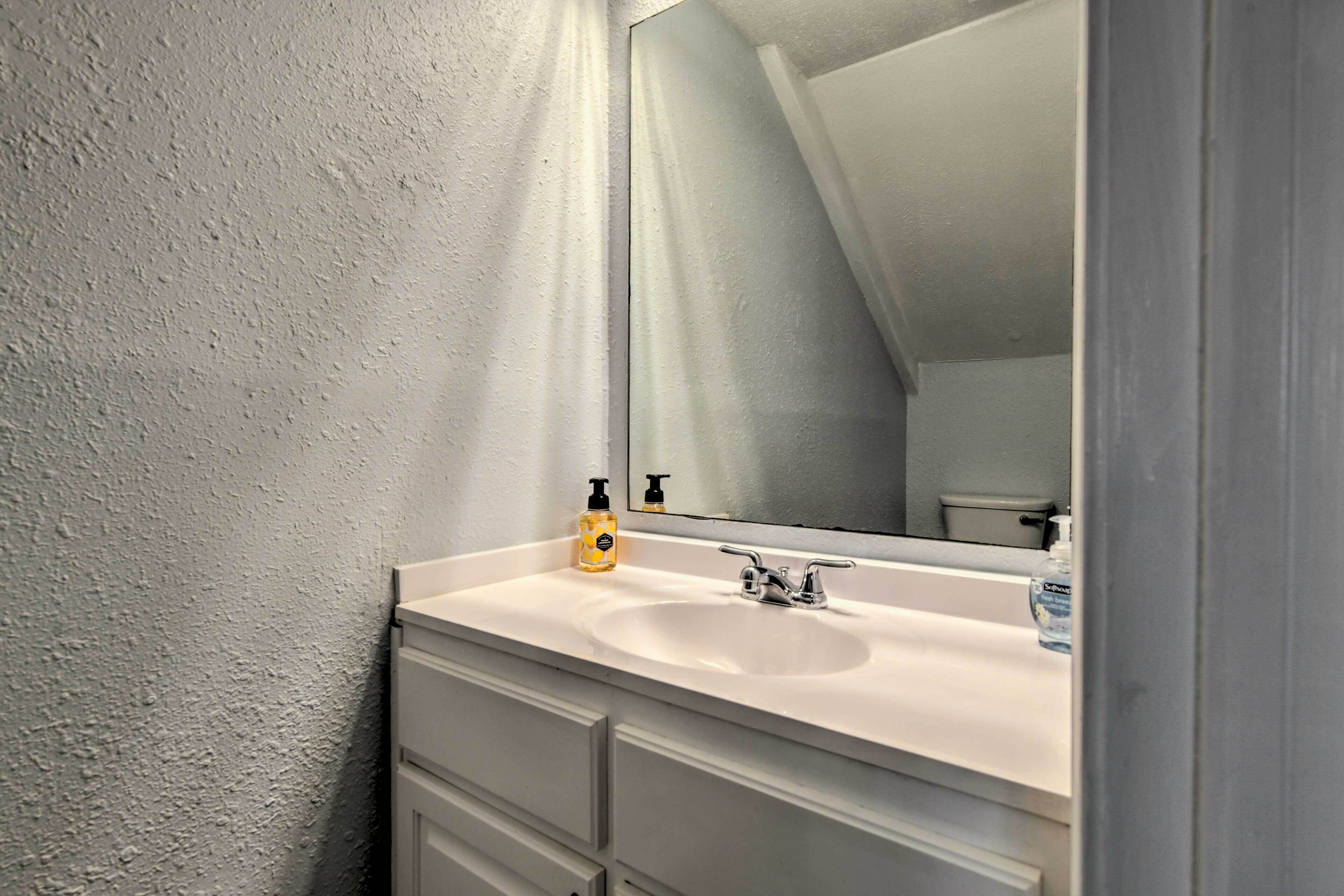 Une salle de bain avec un lavabo blanc, un miroir et un flacon de savon pour les mains.