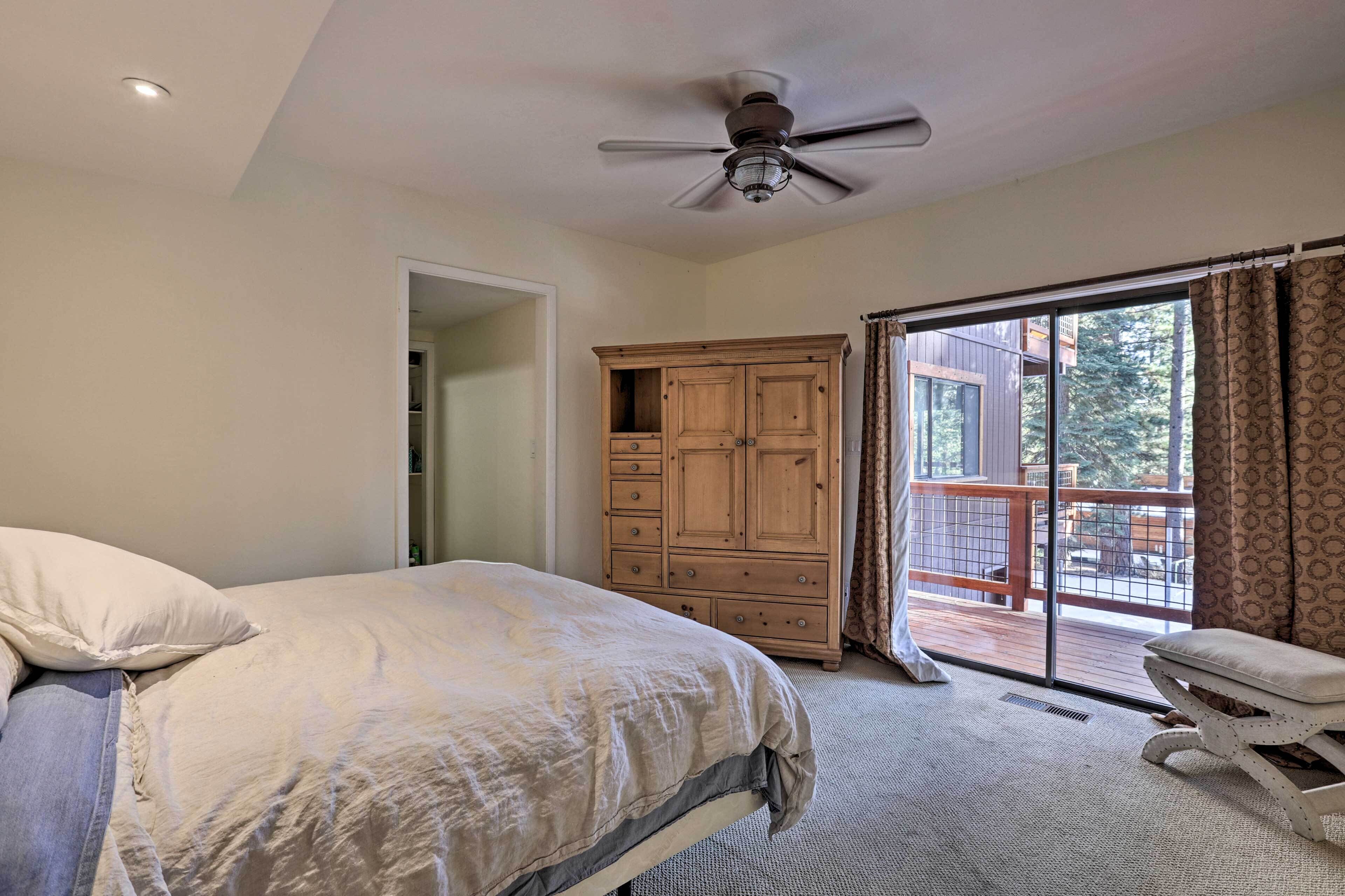 A bedroom with a bed, a wooden wardrobe, a ceiling fan, and a balcony with a view of the outdoors.