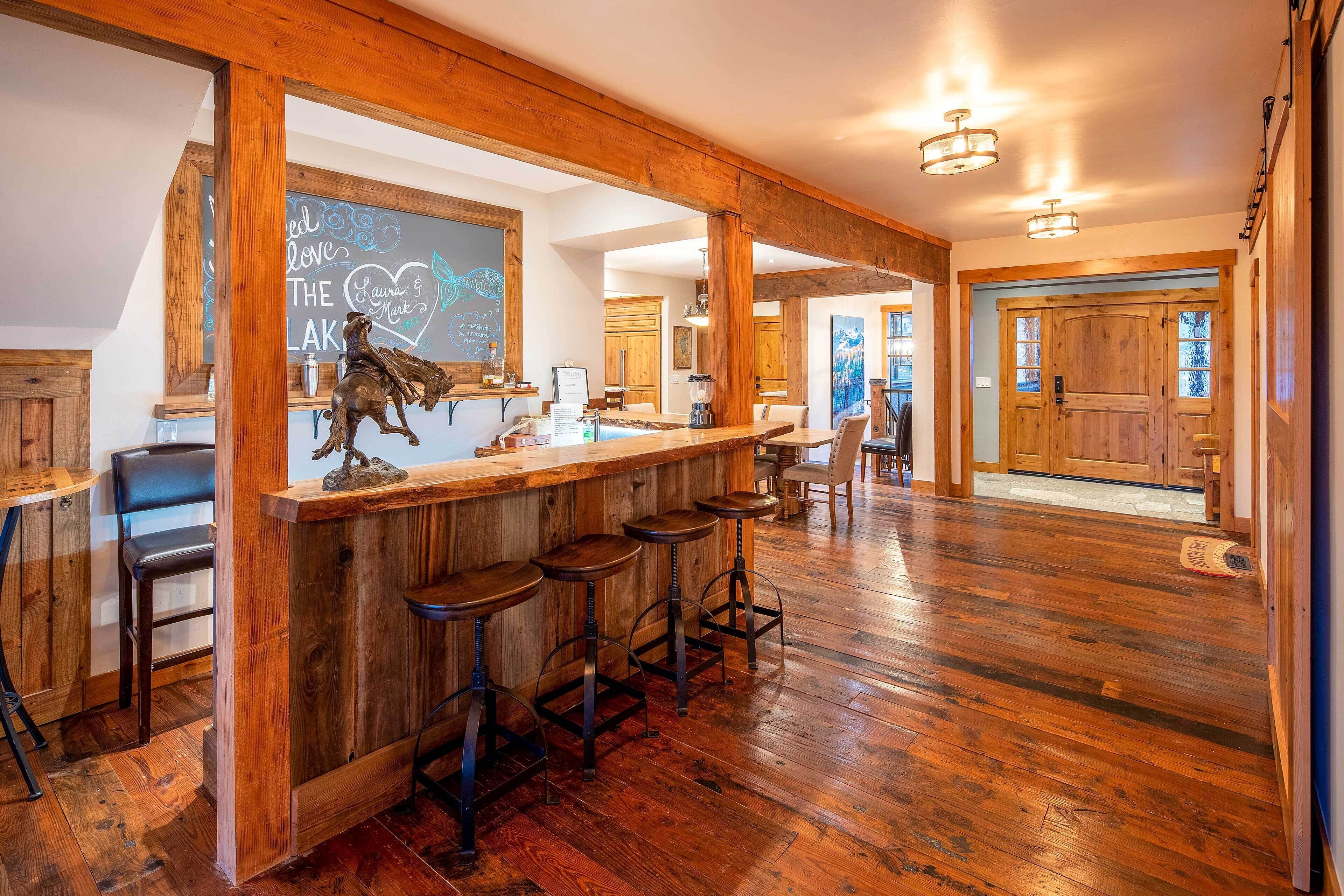 A rustic bar area with wooden beams, a chalkboard with writing, and a horse sculpture.