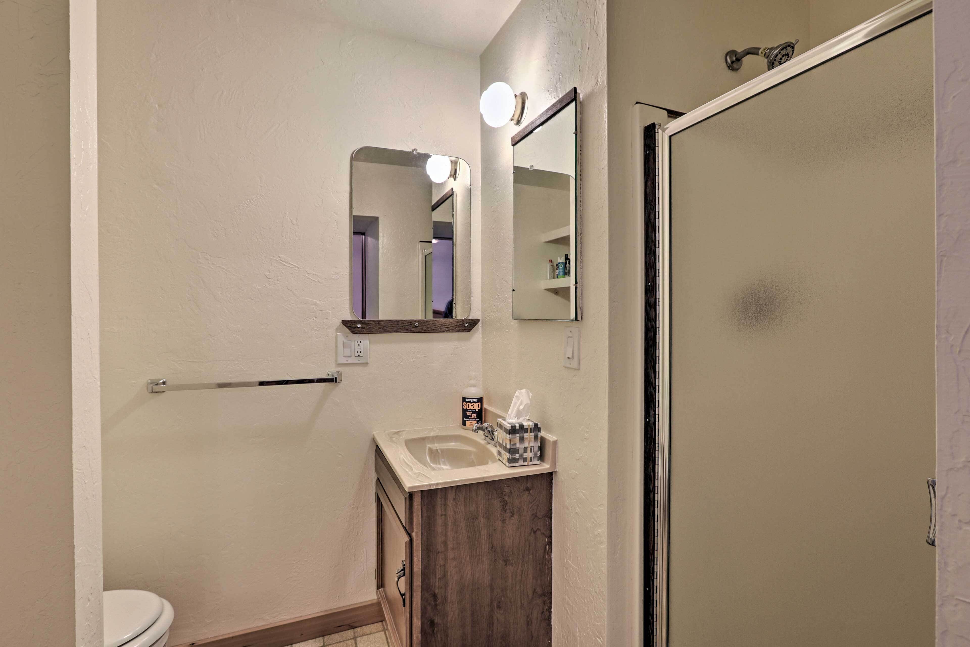 A bathroom with a toilet, sink, mirror, and shower door.