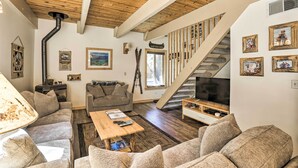 Un salón acogedor con techo de madera, una escalera y un televisor.