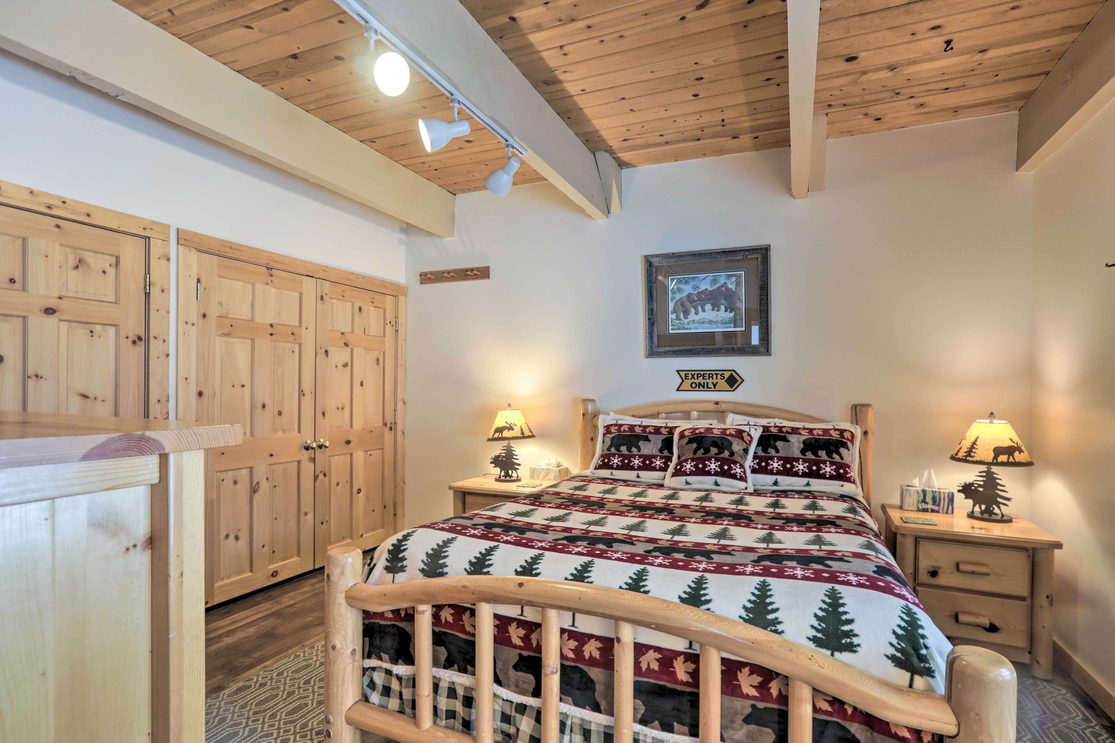 Un dormitorio acogedor con techo de madera, una cama con colcha festiva, dos mesitas de noche con lámparas y un cuadro enmarcado en la pared.