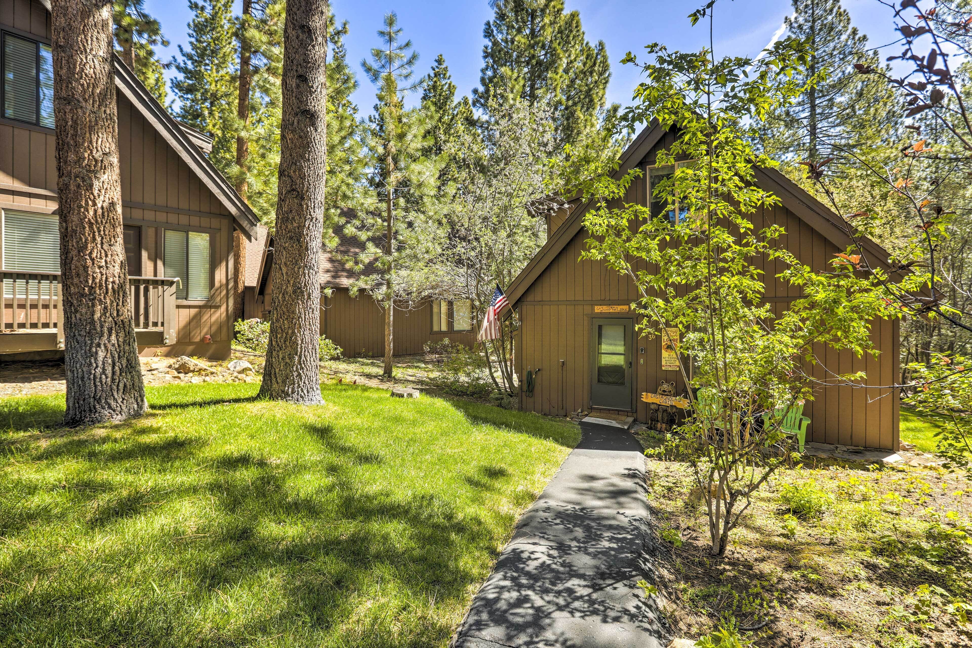 Une cabane aux murs en bois, entourée de grands arbres et d’une pelouse bien entretenue.