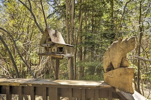 Una terraza de madera con un comedero para pájaros y una escultura de madera tallada.