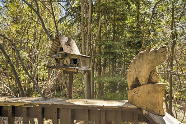 A wooden deck with a birdhouse and a carved wooden sculpture.