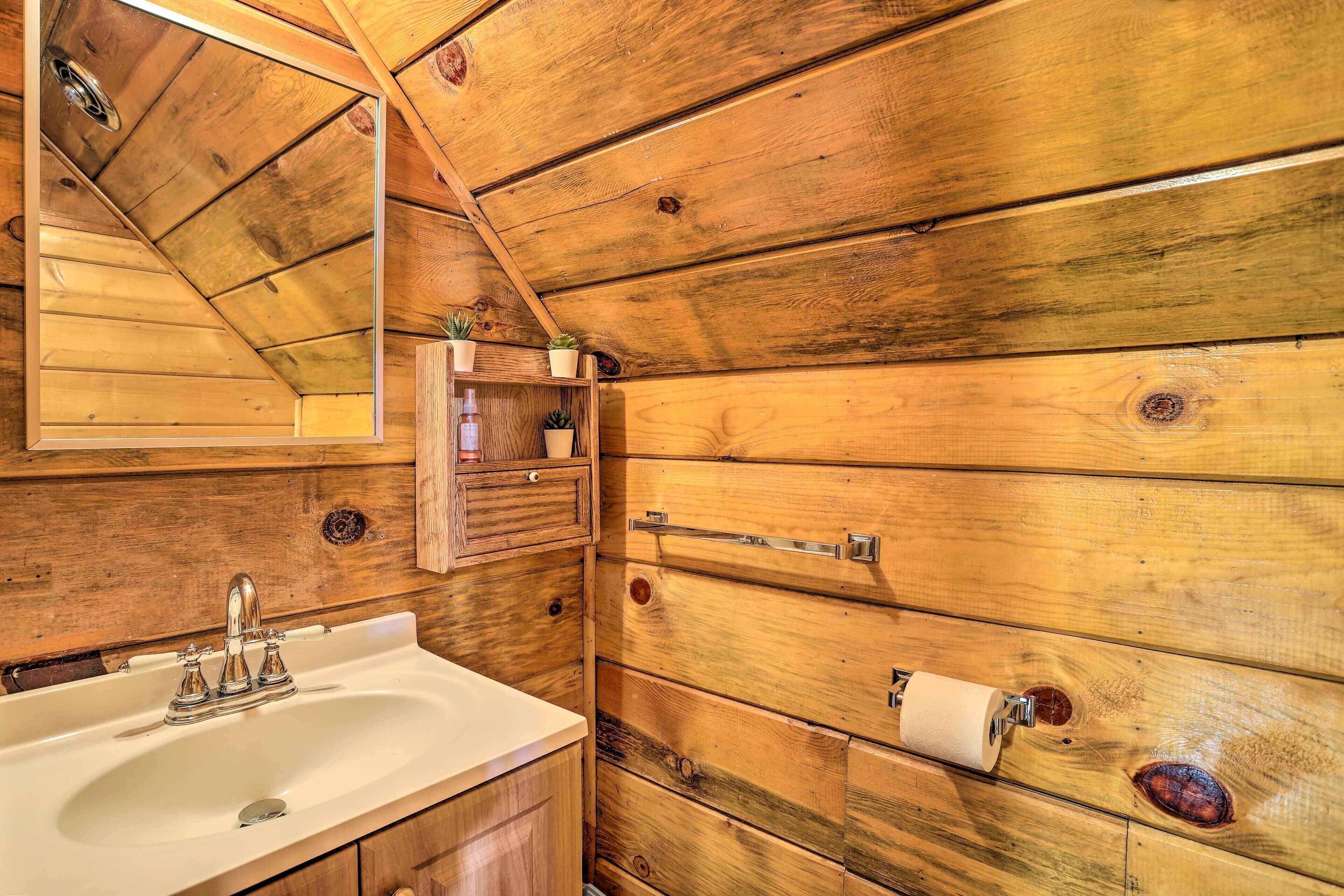 Een houten badkamer in een vakantiehuisje, met een wastafel, spiegel en handdoekhouder.