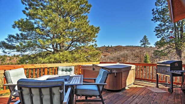 A deck with outdoor furniture, a hot tub, and a grill.