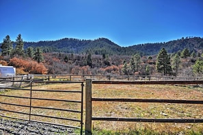 A fenced outdoor area with a clear view of a forested mountain range.