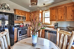 A kitchen with wooden cabinets, stainless steel appliances, and a vase with dried plants on the table. - Pagosa Springs Escape w/ Deck, Hot Tub & Grill! (Pagosa Springs)