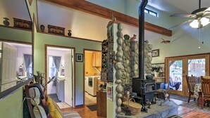 A cozy living room with a stone fireplace, a sofa, and a wooden ceiling. - Secluded Placerville Cabin w/ Deck: Walk to River! (Placerville)