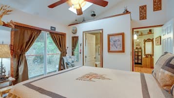 Un dormitorio con una cama grande, un ventilador de techo y vistas al exterior a través de la ventana.