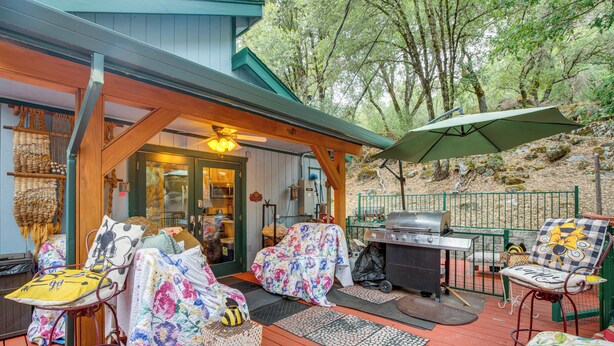A covered outdoor deck with seating, a grill, and a covered entrance. - Secluded Placerville Cabin w/ Deck: Walk to River! (Placerville)