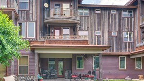 A multi-story wooden building with balconies, a covered patio with outdoor seating, and a stone wall. - < 1 Mi to Hot Spring: Condo in Pagosa Springs! (Pagosa Springs)