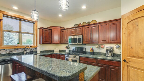 A kitchen with granite countertops, wooden cabinets, stainless steel appliances, and a large island. - < 1 Mi to Hot Spring: Condo in Pagosa Springs! (Pagosa Springs)