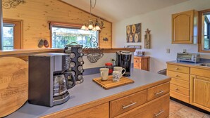 A kitchen with wooden cabinets, a coffee maker, and a wooden cutting board with mugs. - Ski, Soak & Explore! Spacious Pagosa Springs Home (Pagosa Springs)