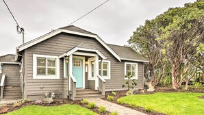 A residential house with a front porch, a small garden, and a tree in the background. - Chic Lincoln City Retreat on Oregon Coast (Lincoln City)