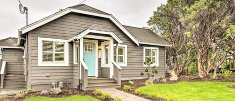 A residential house with a front porch, a small garden, and a tree in the background.