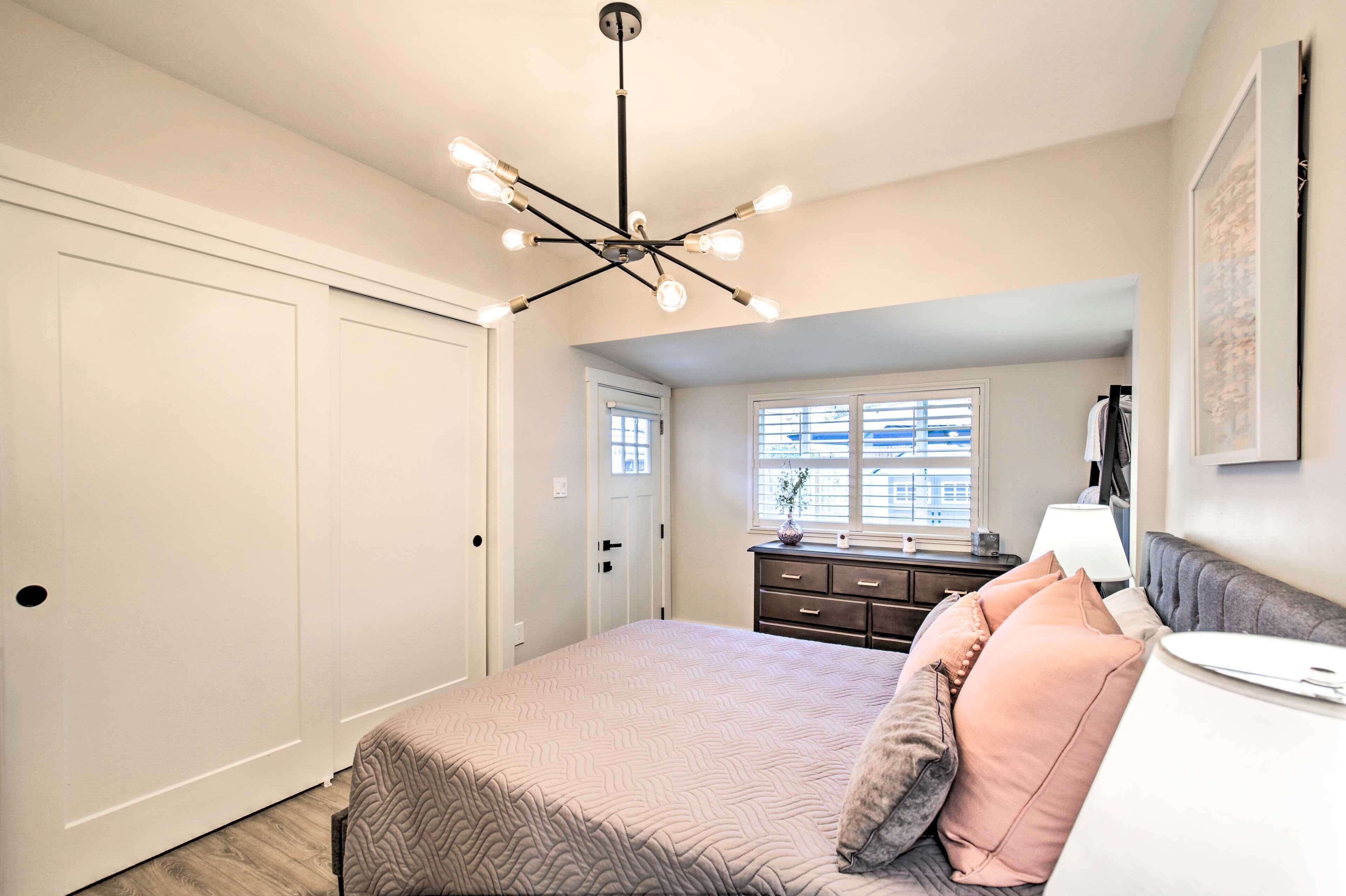 A bedroom with a bed, bedside table, lamp, and a window with blinds.