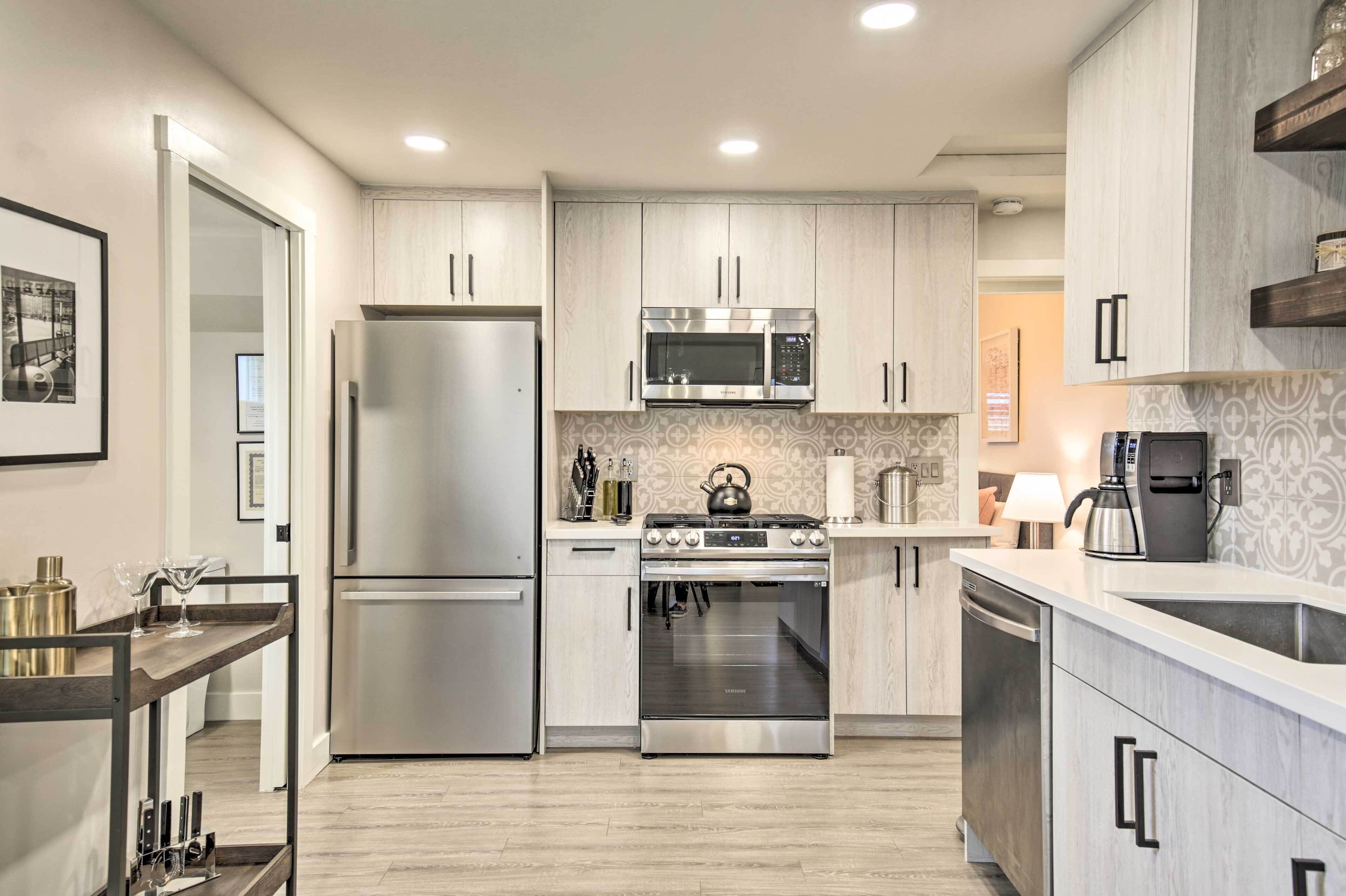A modern kitchen with stainless steel appliances, light wood cabinets, and a central island.