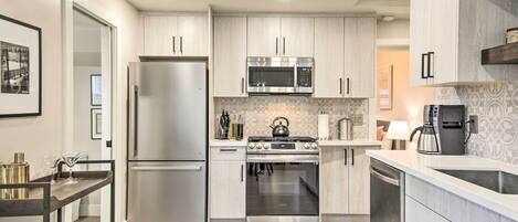 A modern kitchen with stainless steel appliances, light wood cabinets, and a central island.