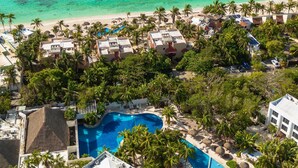 Ein Luftbild eines Resorts mit großem Schwimmbad, Strand und Meer.
