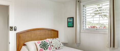 A bedroom with a bed, a ceiling fan, a window with curtains, and a framed picture on the wall.