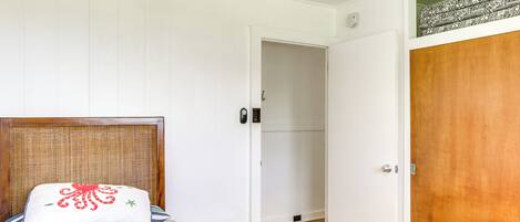 A bedroom with a bed, a bedside table, a wooden door, and a white wall.