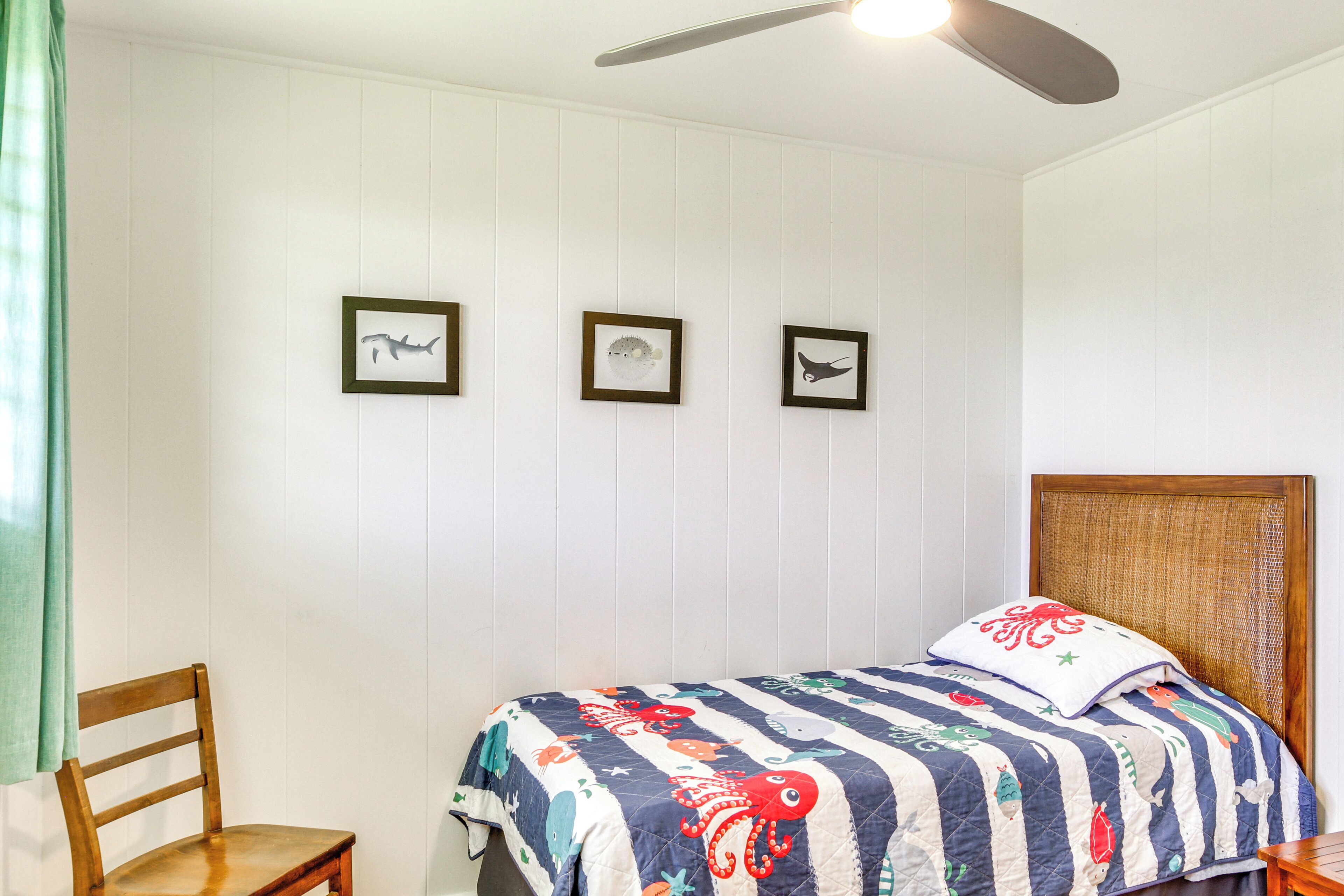A bedroom with a bed, a chair, and three framed pictures on the wall.