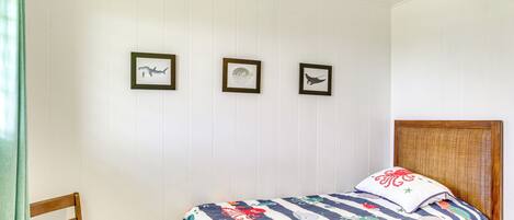 A bedroom with a bed, a chair, and three framed pictures on the wall.