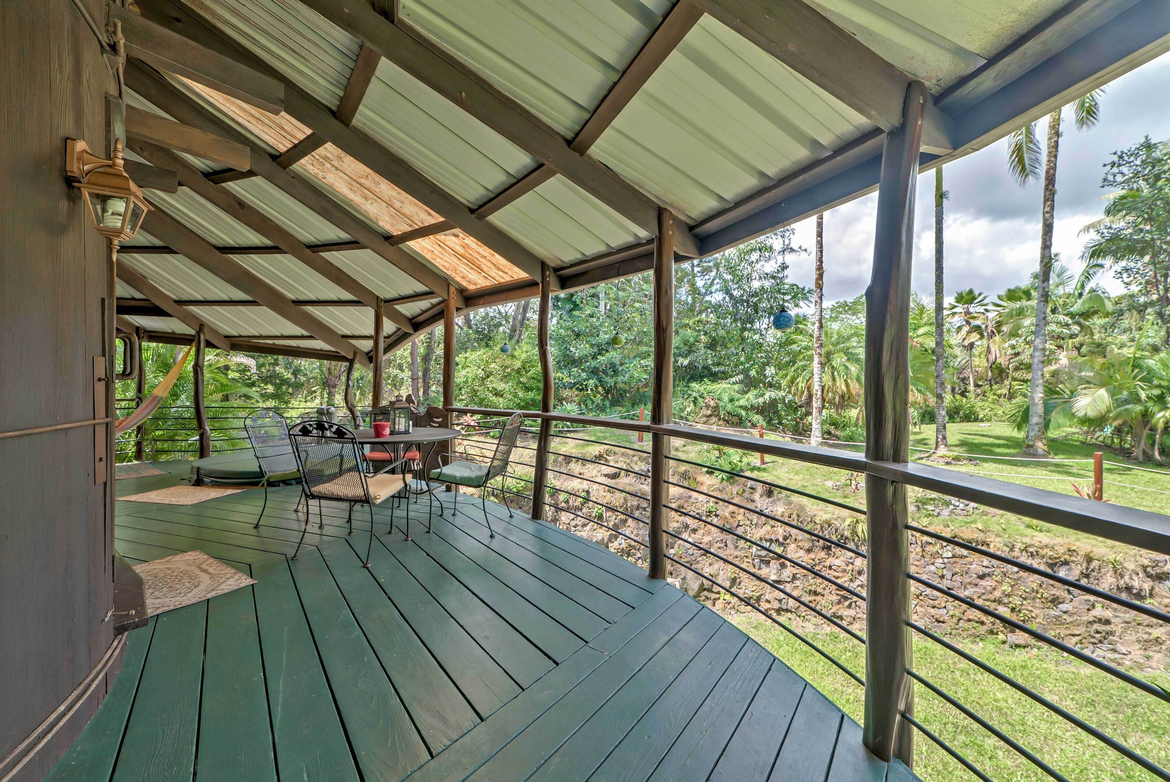 A covered outdoor area with a wooden deck, metal railing, and a table with chairs.