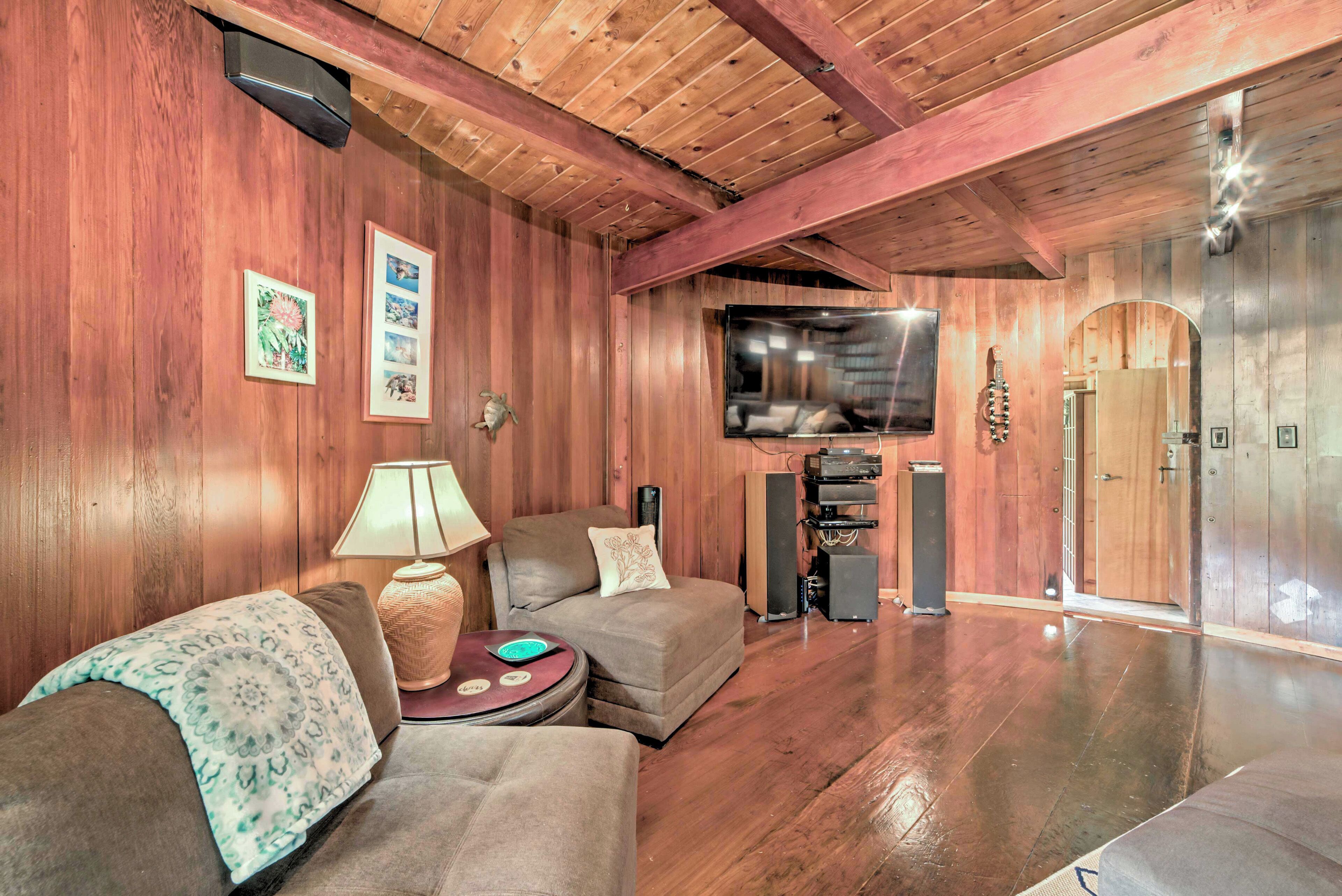 Una habitación con paneles de madera, un sofá, un televisor y un equipo de sonido.