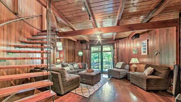 A wooden interior with a staircase, two sofas, a coffee table, and a lamp. - Tropical Cabana w/ Deck, Hot Tub & Lush Scenery! (Keaau)