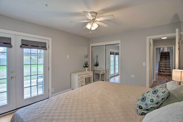 A bedroom with a large bed, a ceiling fan, a dresser, and a mirror.