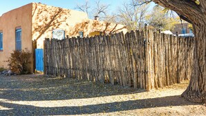 A rustic wooden fence in front of a building with a blue door and windows. - Cozy Adobe Casita: 1 Mile to Santa Fe Plaza! (Santa Fe)