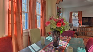 A dining area with a table set for two, a vase of flowers, and a fireplace in the background. - Cozy Adobe Casita: 1 Mile to Santa Fe Plaza! (Santa Fe)