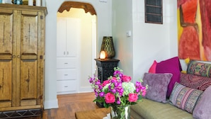 A living room with a wooden cabinet, a sofa with colorful cushions, and a vase with flowers. - Cozy Adobe Casita: 1 Mile to Santa Fe Plaza! (Santa Fe)