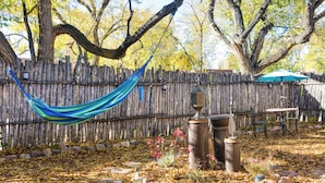 A hammock hanging between trees, a wooden fence, and a patio area with a table and chairs. - Cozy Adobe Casita: 1 Mile to Santa Fe Plaza! (Santa Fe)