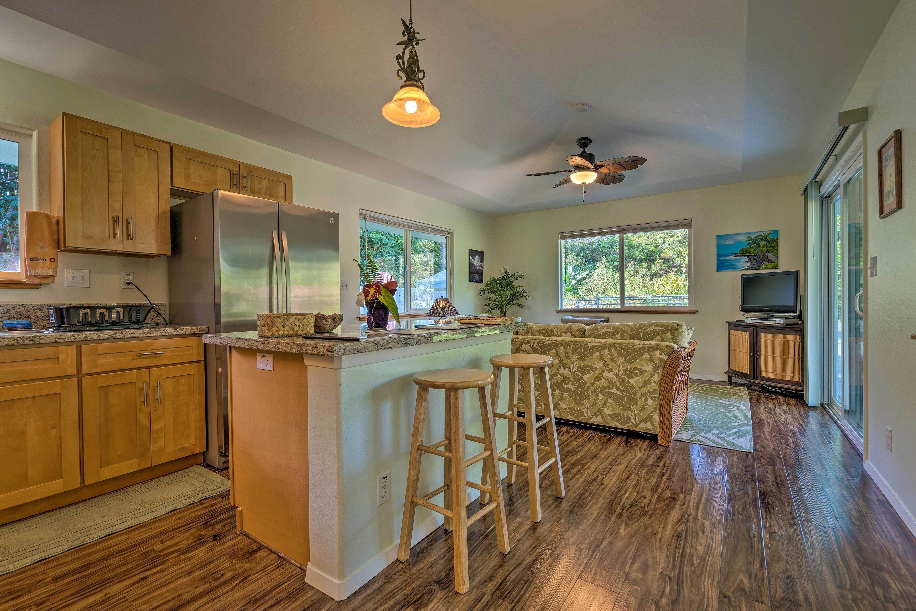A kitchen with wooden cabinets, a stainless steel refrigerator, and a bar area with stools.
