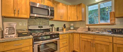 A kitchen with wooden cabinets, a stainless steel microwave, a gas stove, and a built-in oven.