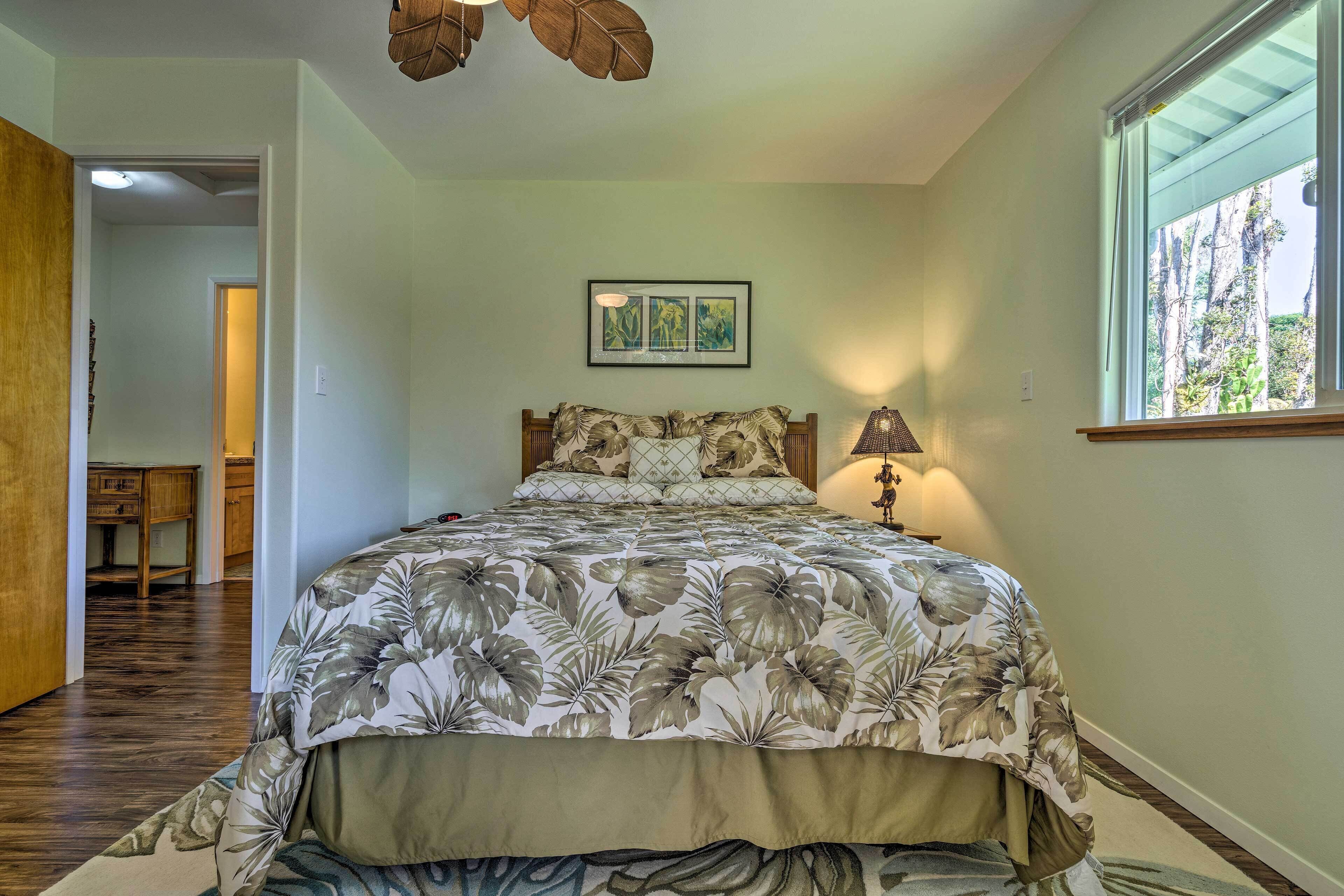 A bedroom with a floral bedspread, a wooden headboard, a bedside lamp, and a framed picture on the wall.