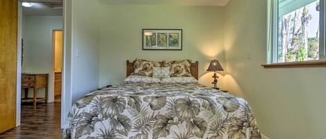 A bedroom with a floral bedspread, a wooden headboard, a bedside lamp, and a framed picture on the wall.