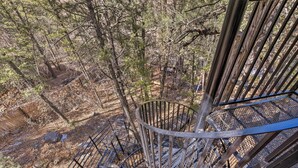 Uma escadaria em espiral cercada por árvores numa área arborizada.